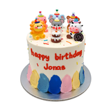 round cake with animals topper with icing rainbow at the bottom.